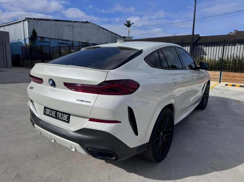 White 2022 BMW X6 xDrive40i M Sport, rear three-quarter view, available for hire in Sydney
